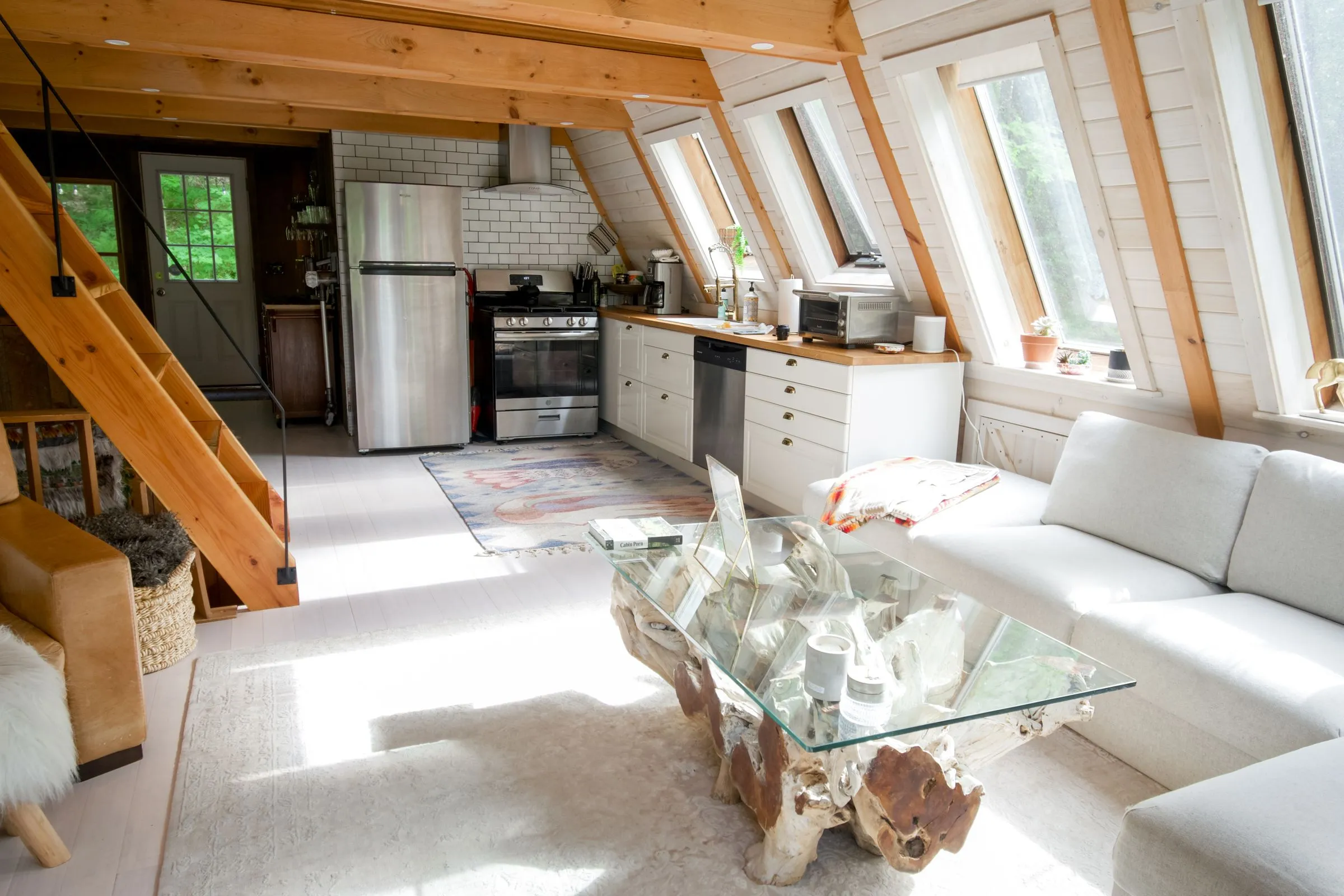 An open kitchen and sitting area under a timber roof, with a staircase to a loft