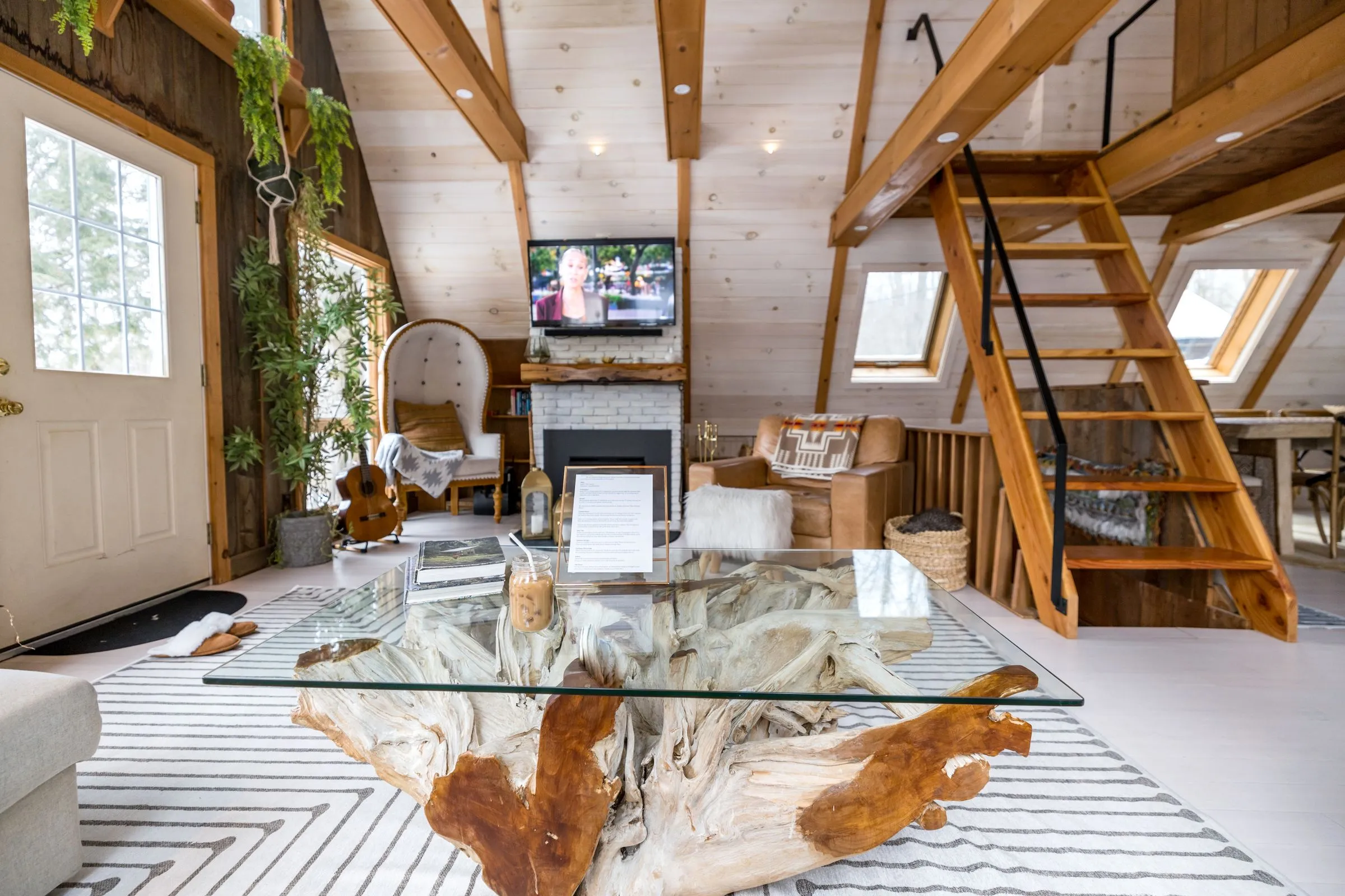 A living room under a steep timber roof, with a sofa and a big window